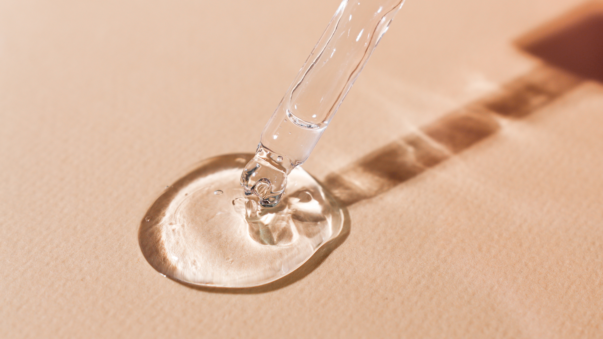 goutte d'huile essentielles sur un fond rose ensoleillé